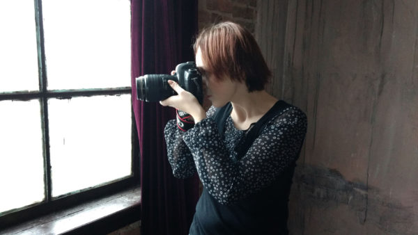 Юля Філіровська знімає своєю камерою Canon 3D Mark II щось у вікні. 